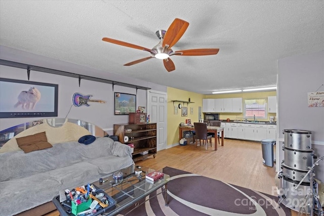 living area featuring a textured ceiling, light wood finished floors, and a ceiling fan