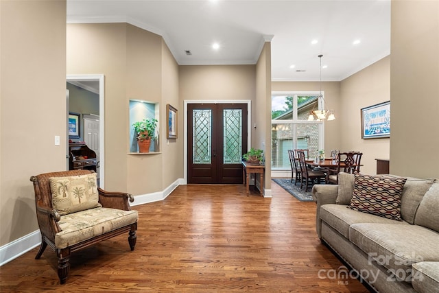 foyer with french doors, a chandelier, hardwood / wood-style flooring, and crown molding