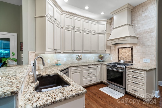 kitchen with gas range, custom exhaust hood, light stone counters, and backsplash