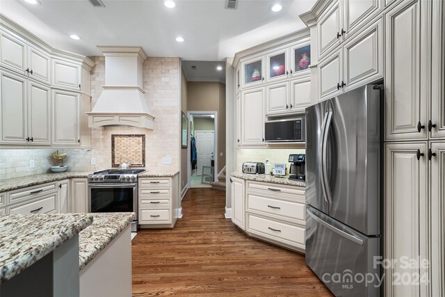 kitchen with backsplash, dark hardwood / wood-style floors, premium range hood, and stainless steel appliances