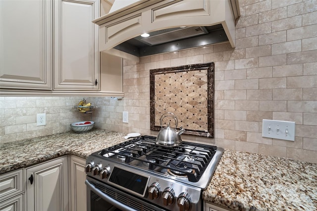 kitchen with decorative backsplash, stone counters, custom range hood, and gas range