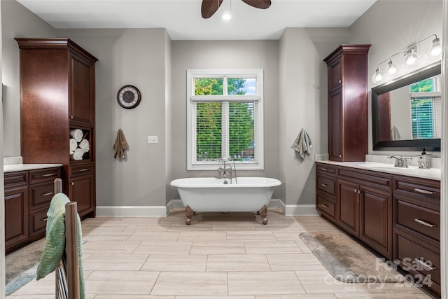 bathroom with tile patterned floors, ceiling fan, vanity, and a washtub