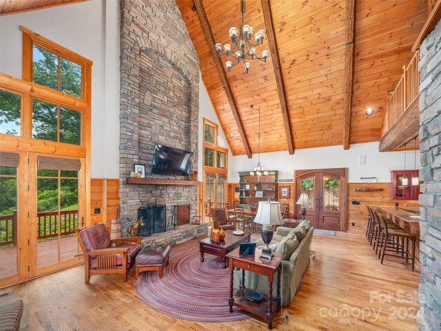 living room with high vaulted ceiling, a fireplace, and a notable chandelier