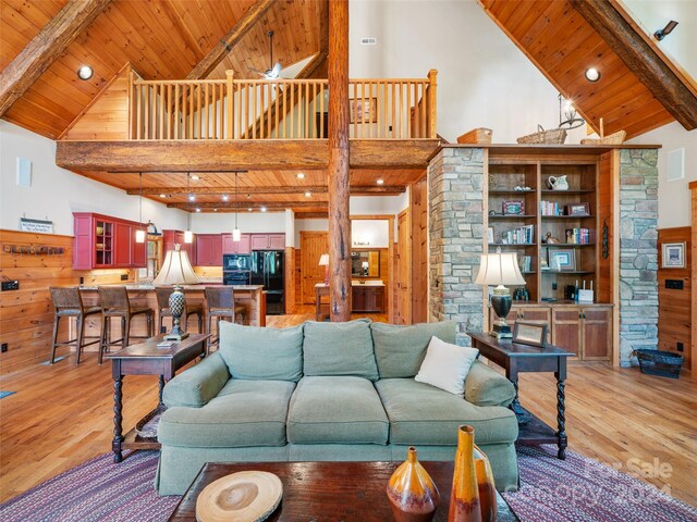 living room with beamed ceiling, high vaulted ceiling, and light hardwood / wood-style flooring