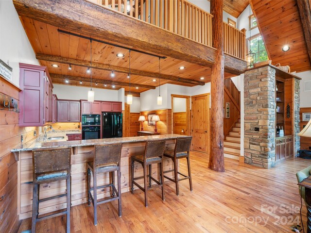 kitchen with light hardwood / wood-style flooring, black appliances, light stone counters, kitchen peninsula, and sink