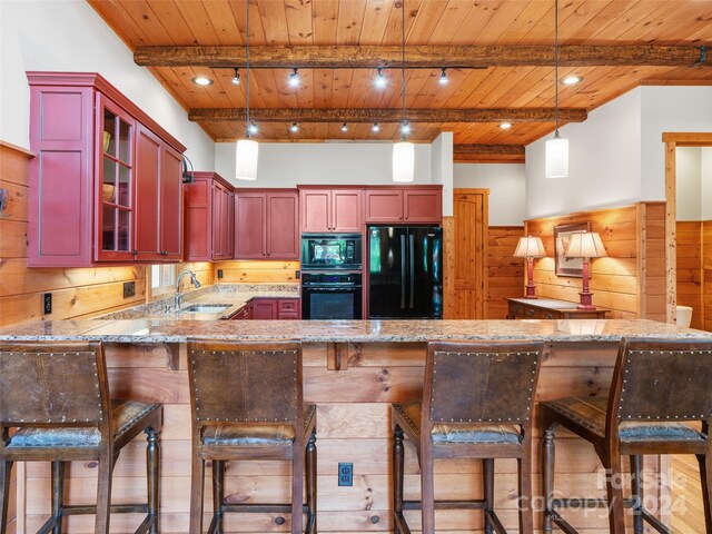 kitchen with hanging light fixtures, light stone counters, sink, black appliances, and kitchen peninsula