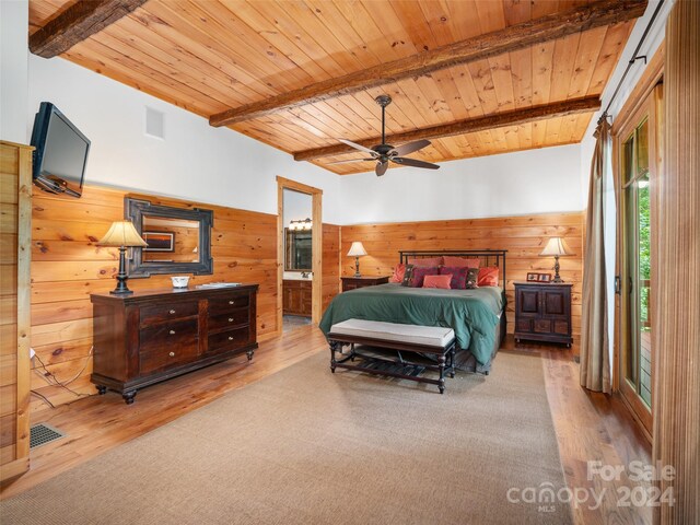 bedroom with hardwood / wood-style flooring, wooden walls, beam ceiling, and ensuite bathroom