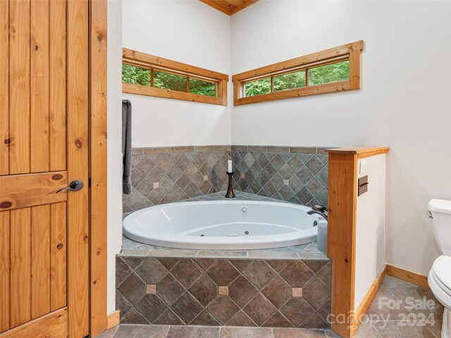 bathroom featuring tile patterned flooring, toilet, and tiled tub