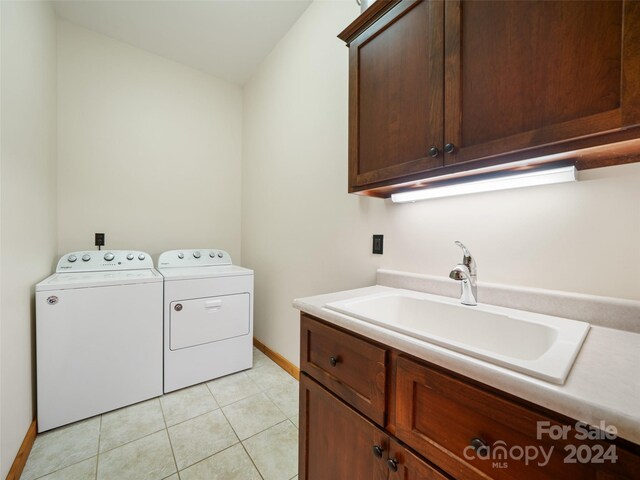 clothes washing area featuring separate washer and dryer, light tile patterned floors, cabinets, and sink