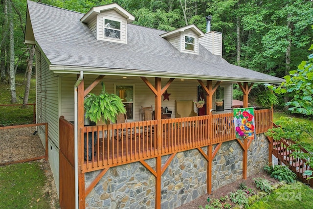 exterior space with a deck and roof with shingles