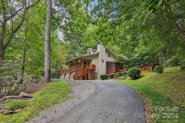 view of front of home featuring driveway, a sunroom, a chimney, stairway, and an attached garage