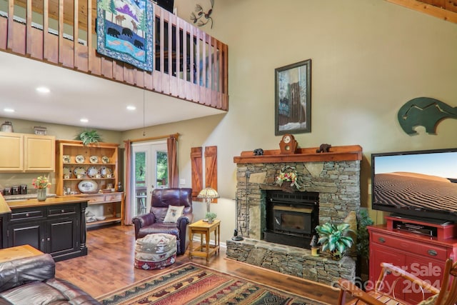 living area featuring recessed lighting, french doors, wood finished floors, and a stone fireplace