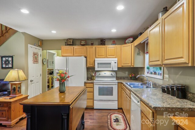 kitchen with light brown cabinets, dark hardwood / wood-style flooring, sink, a center island, and white appliances