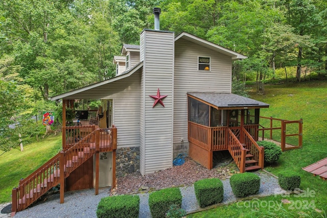 view of side of home featuring a lawn, a wooden deck, and a sunroom