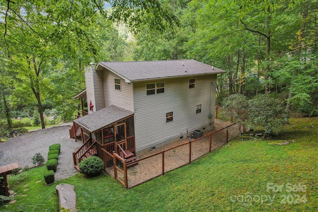 back of house with driveway, a sunroom, crawl space, a yard, and central AC