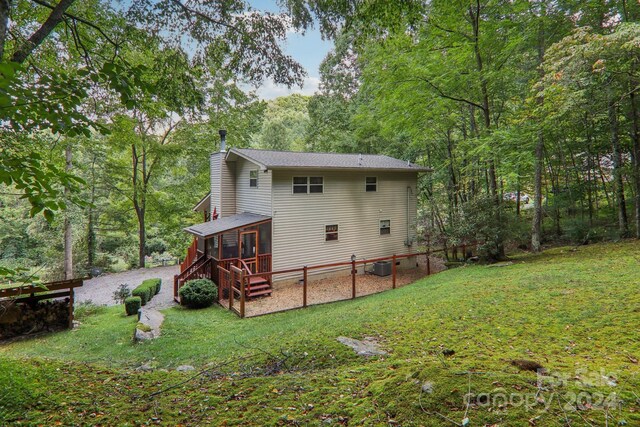 rear view of property with central AC, a wooden deck, and a lawn