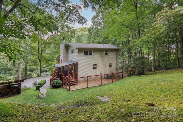 back of house featuring central AC unit, a lawn, a sunroom, and stairway