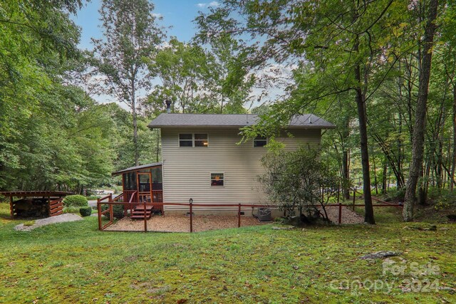 rear view of property featuring a lawn, cooling unit, and a deck