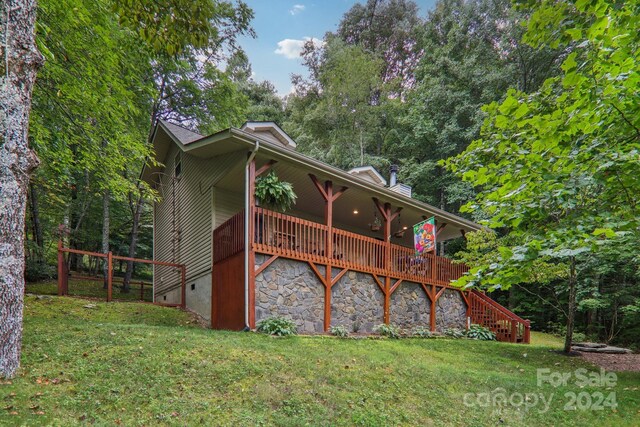 rear view of house featuring a wooden deck and a yard