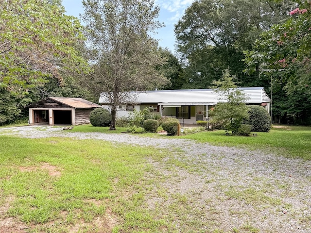 view of front of house featuring a porch, an outbuilding, a detached garage, and a front yard