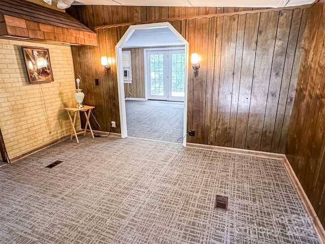 empty room featuring carpet, vaulted ceiling, brick wall, and wooden walls