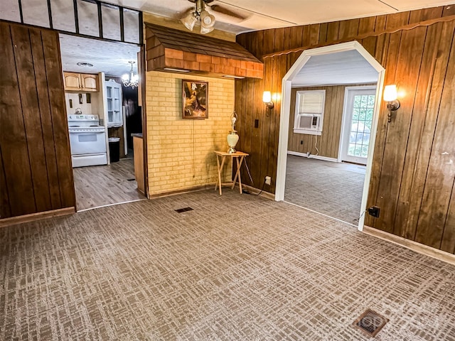 unfurnished room with ceiling fan, brick wall, light colored carpet, wood walls, and cooling unit