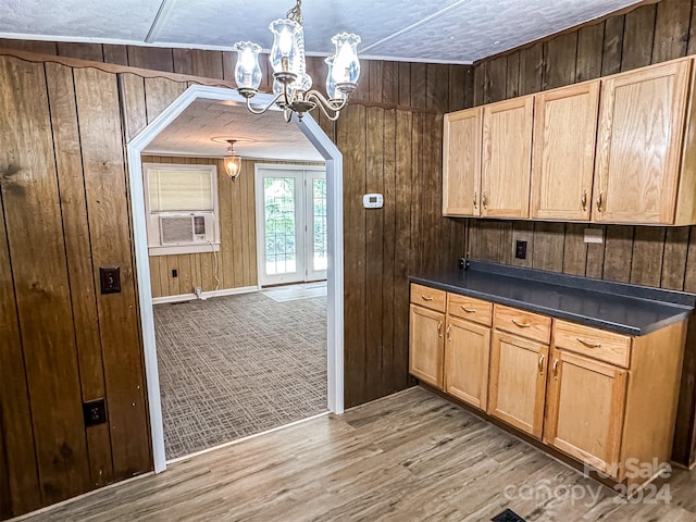 kitchen featuring light hardwood / wood-style flooring, wooden walls, and decorative light fixtures