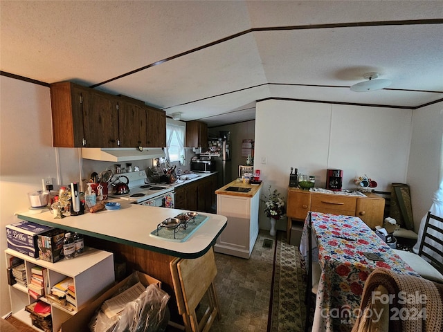 kitchen featuring a textured ceiling, a peninsula, white electric range, light countertops, and a kitchen bar