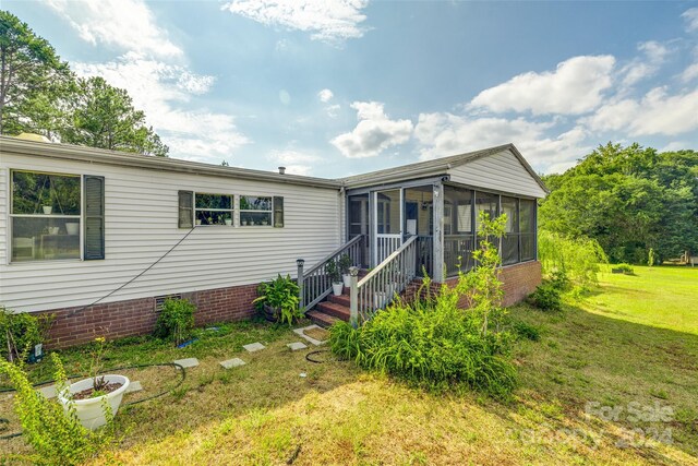 view of front of house with a front yard and a sunroom