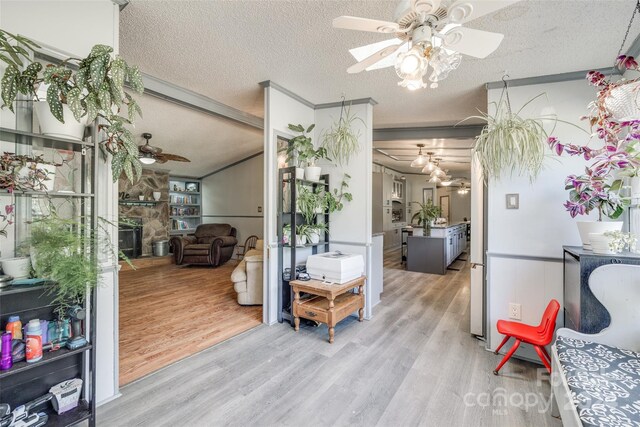 interior space with a textured ceiling, light wood-type flooring, and ceiling fan