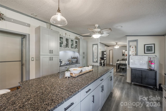 kitchen featuring white cabinetry, dark wood-type flooring, a textured ceiling, and decorative light fixtures