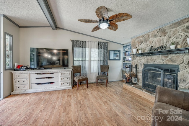 living room with light hardwood / wood-style floors, a textured ceiling, lofted ceiling with beams, and a fireplace