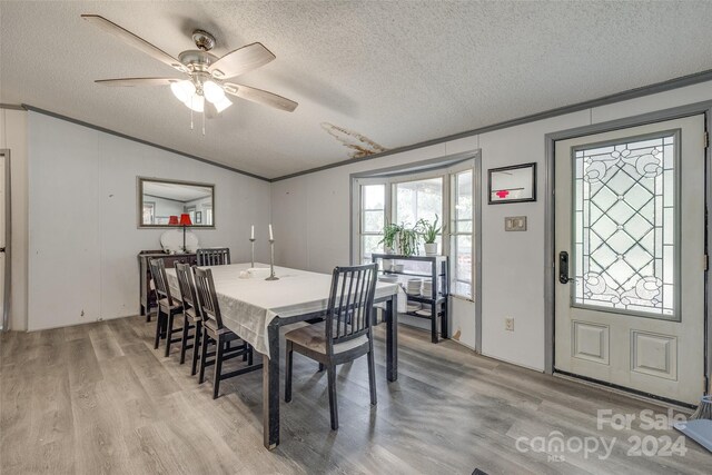 dining space featuring a textured ceiling, ceiling fan, light wood-type flooring, and vaulted ceiling