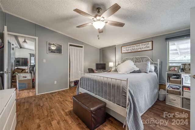 bedroom featuring a textured ceiling, hardwood / wood-style flooring, ceiling fan, and vaulted ceiling