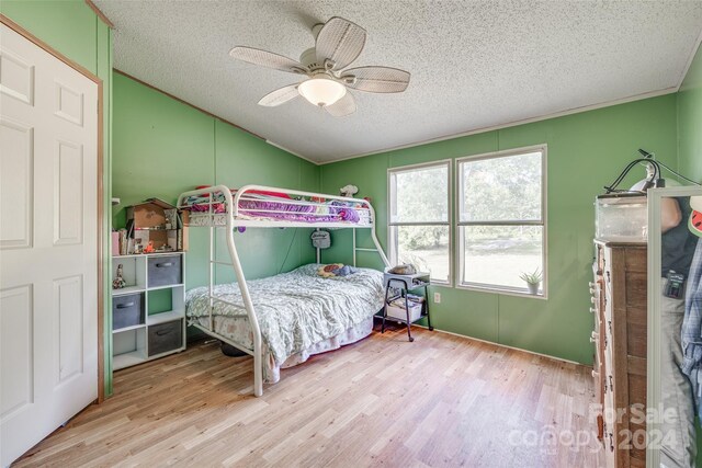 bedroom with a textured ceiling, light wood-type flooring, and ceiling fan