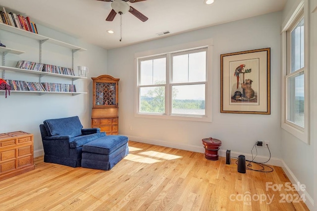 living area featuring light hardwood / wood-style floors and ceiling fan