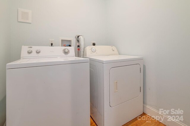 laundry room featuring washing machine and clothes dryer and light hardwood / wood-style flooring