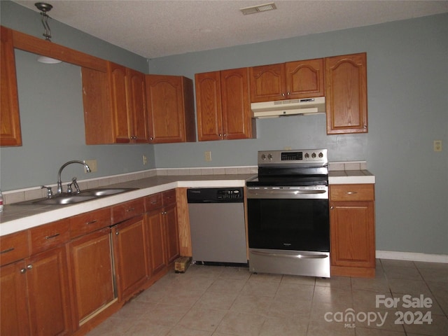 kitchen with sink, light tile patterned flooring, a textured ceiling, and appliances with stainless steel finishes