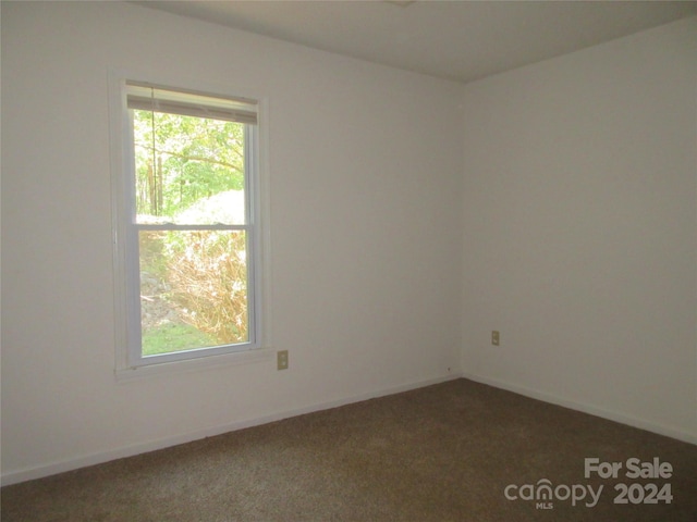 unfurnished room featuring dark colored carpet and plenty of natural light