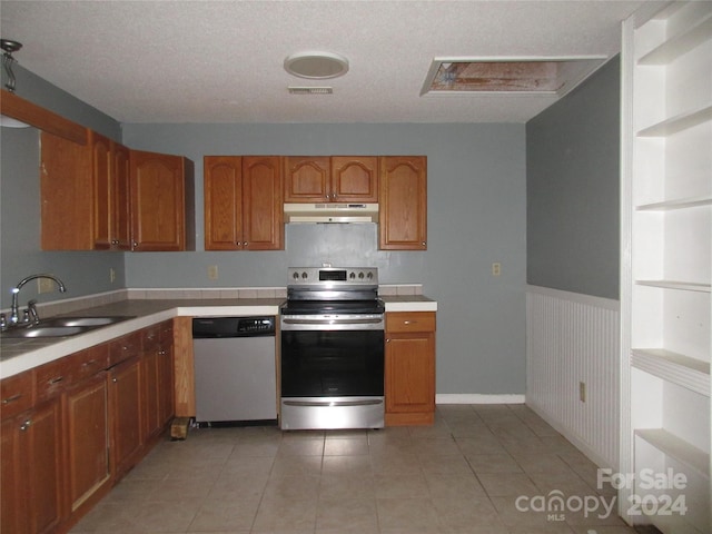 kitchen with sink, light tile patterned floors, built in features, stainless steel appliances, and a textured ceiling