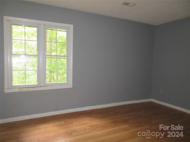 empty room with hardwood / wood-style flooring and plenty of natural light