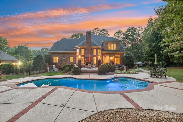 pool at dusk featuring a patio