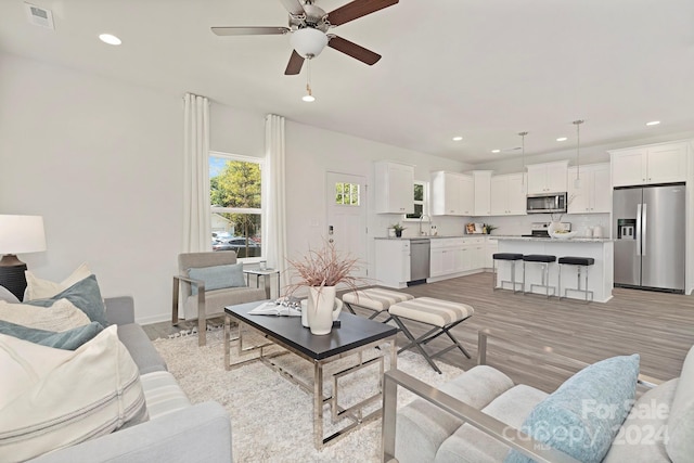 living room featuring ceiling fan, sink, and light hardwood / wood-style flooring