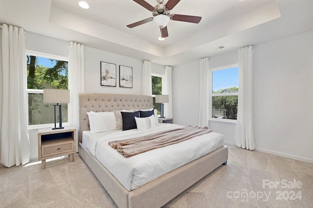 carpeted bedroom featuring ceiling fan and a raised ceiling