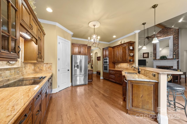 kitchen featuring backsplash, hanging light fixtures, a breakfast bar area, kitchen peninsula, and stainless steel appliances