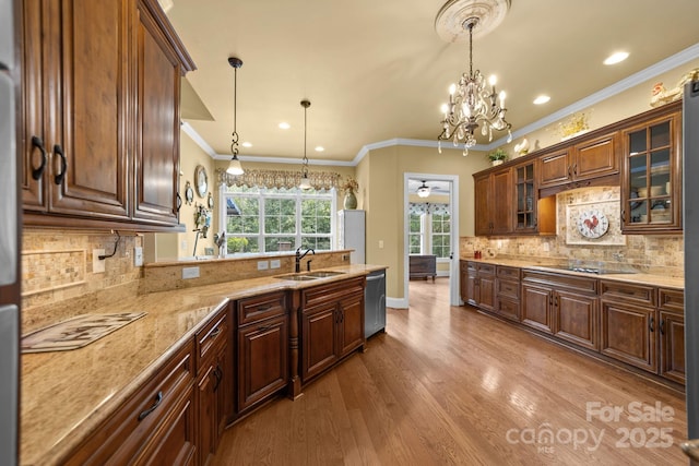 kitchen with ceiling fan with notable chandelier, sink, hanging light fixtures, stainless steel dishwasher, and light stone countertops