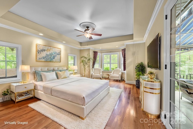 bedroom featuring hardwood / wood-style floors, ceiling fan, a raised ceiling, and ornamental molding