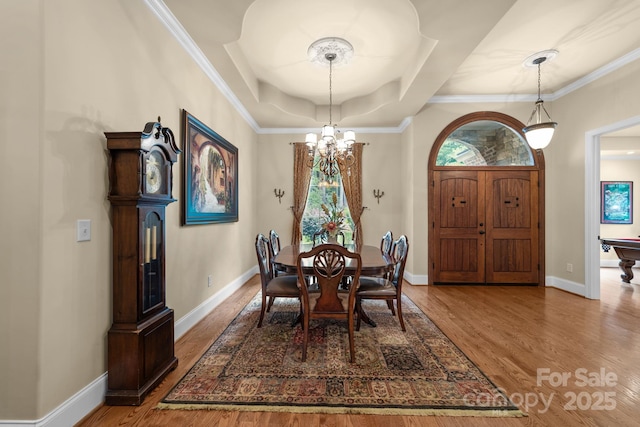 dining area featuring a tray ceiling, an inviting chandelier, hardwood / wood-style flooring, and crown molding