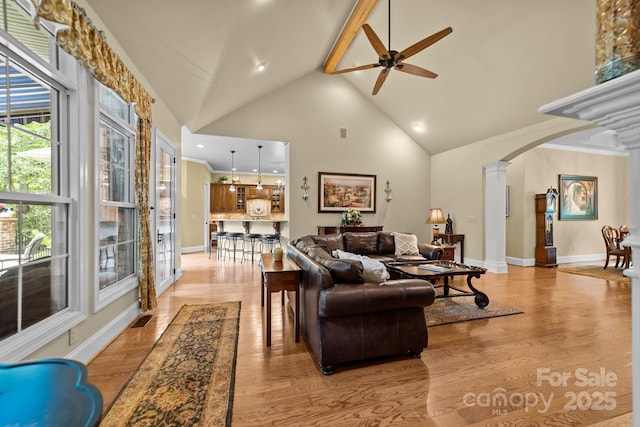 living room with decorative columns, light hardwood / wood-style flooring, ceiling fan, and ornamental molding