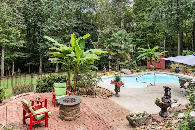 view of swimming pool with a shed, an outdoor fire pit, and a patio